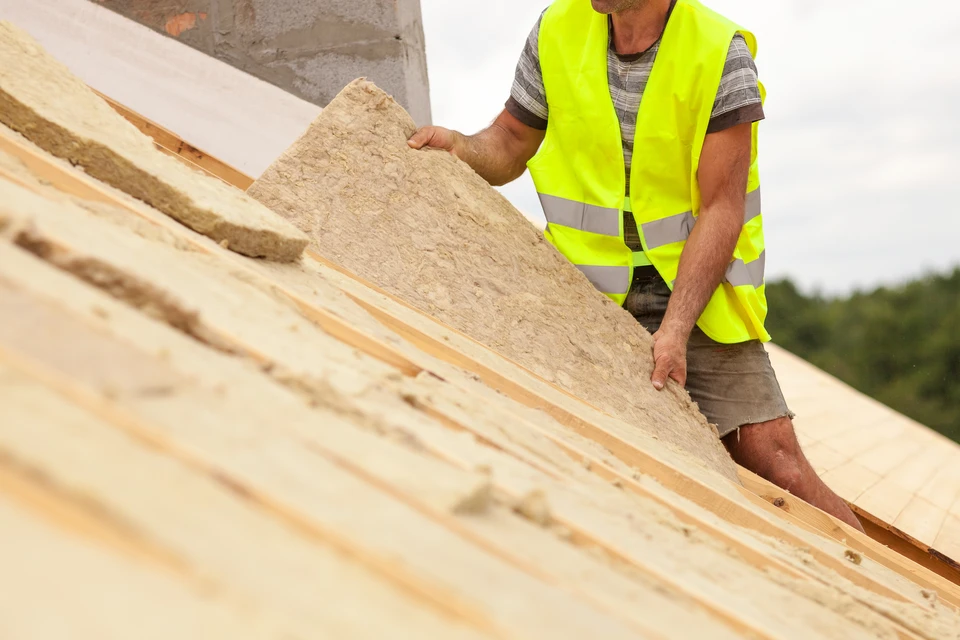 Ouvrier du bâtiment du toit installant du matériau d'isolation du toit sur une nouvelle maison en construction